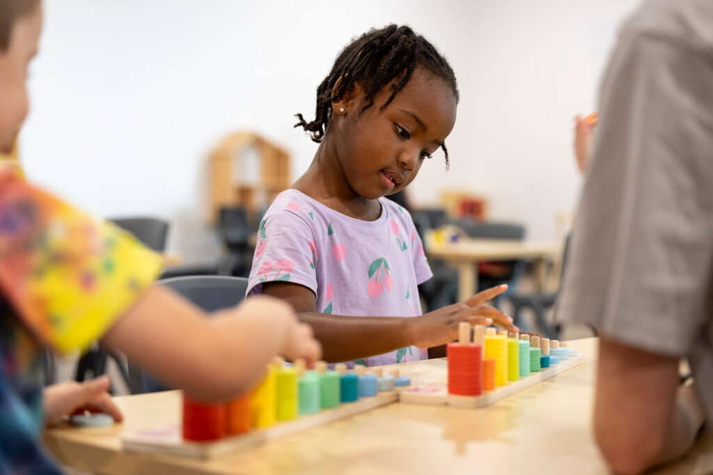 HonourBeenleigh_708w Child engaged in play-based learning with colourful counting blocks at Honour Early Learning’s Free Kindergarten Approved Program in Queensland.